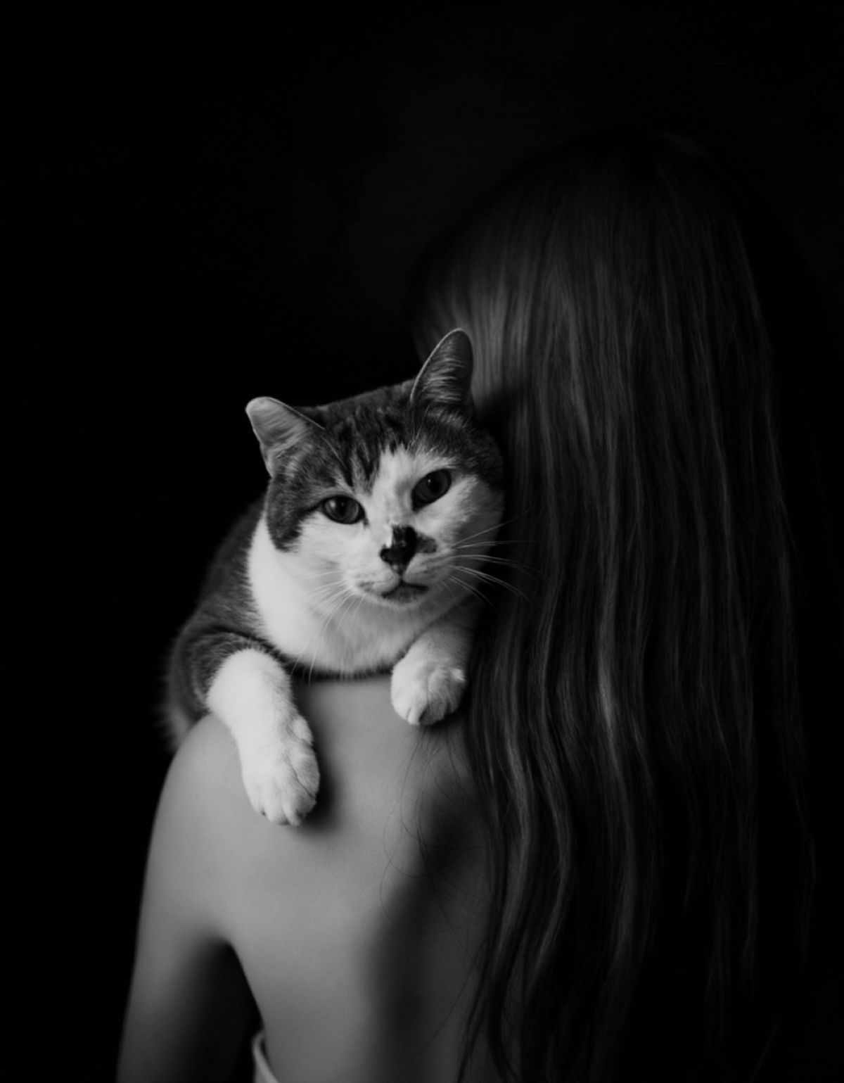 Mujer de espaldas con gato sobre el hombro