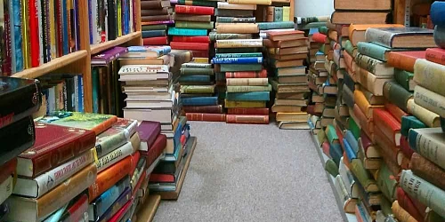 Multiples bloques libros por el suelo y estanterias
